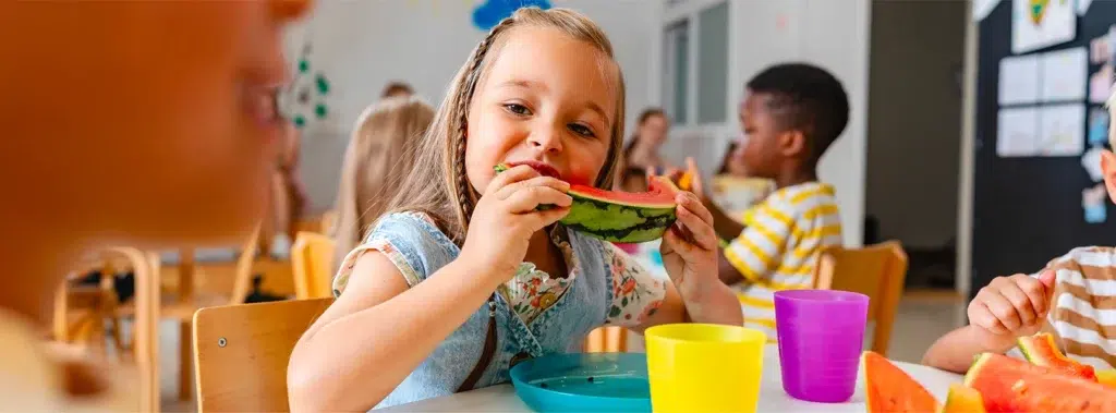 Petite fille mangeant de la pastèque dans une cantine de la SPL Cantines du ponant